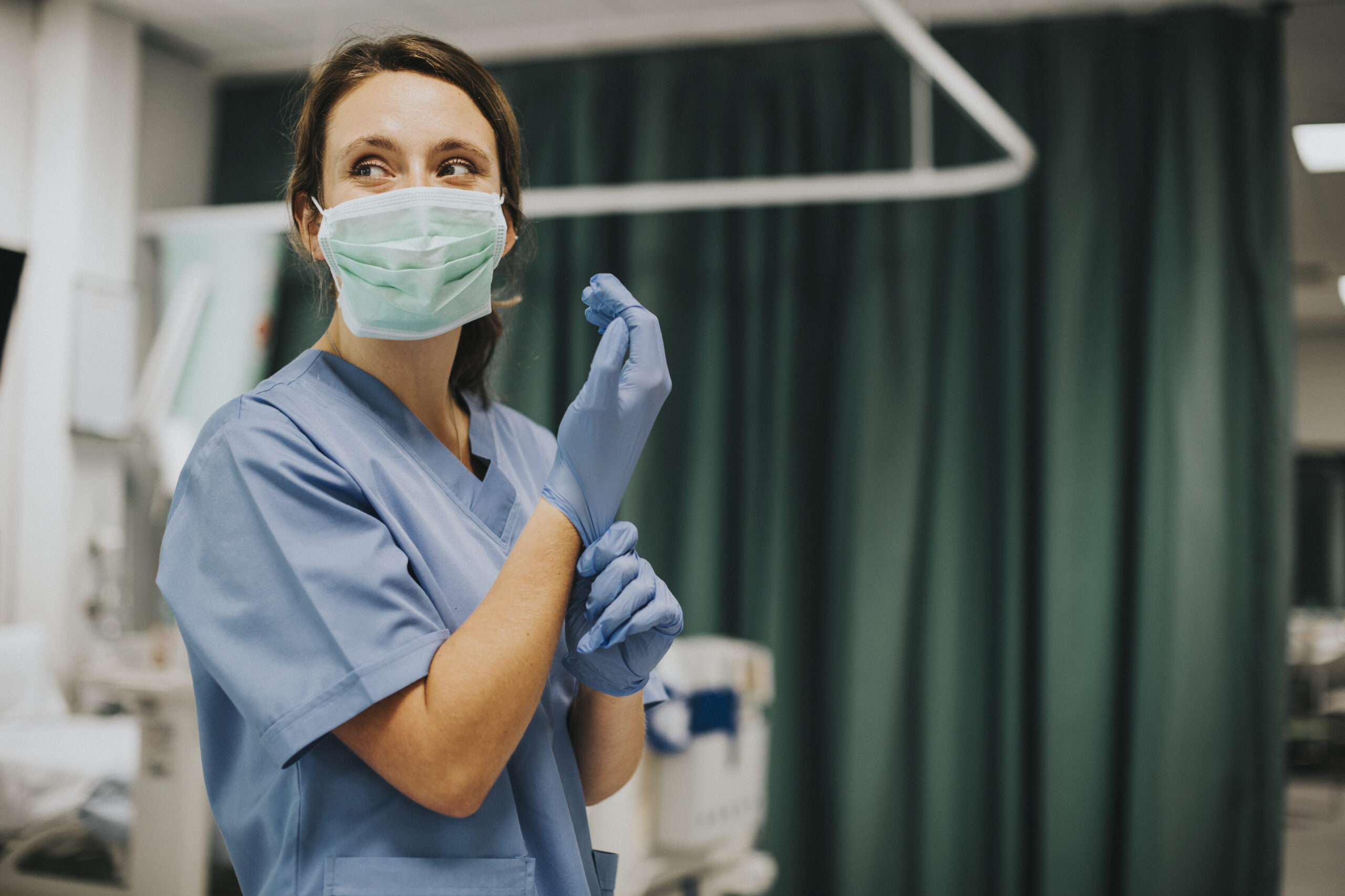 Female nurse with a mask putting on gloves